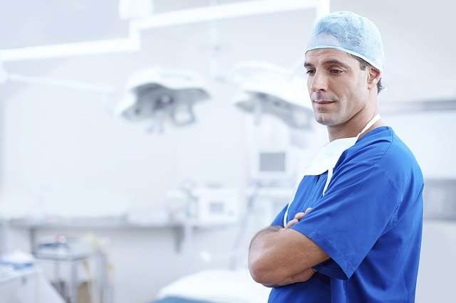 Man in blue scrubs and surgical cap standing in a hospital environment, emphasizing the importance of reliable medical supplies and equipment in healthcare.