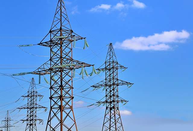 Hoogspanningsleidingen tegen een blauwe lucht, symboliserend duurzame energievoorziening en efficiëntie in de energiesector.