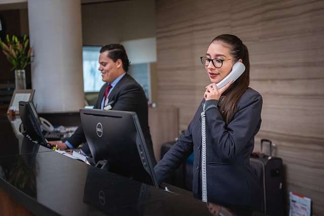Receptionists at a hotel front desk assisting guests with inquiries and services, emphasizing hospitality and customer service in a professional setting.