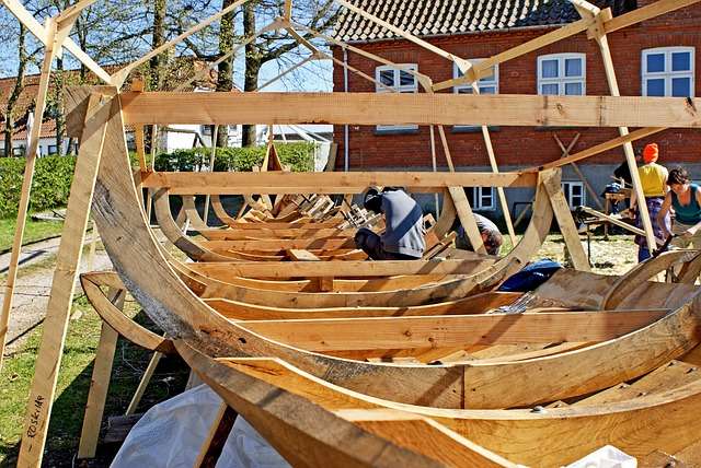 Houtbewerking en scheepsbouw met vakmensen die aan de constructie van houten boten werken, benadrukt de focus op kwaliteit en ambachtelijkheid.