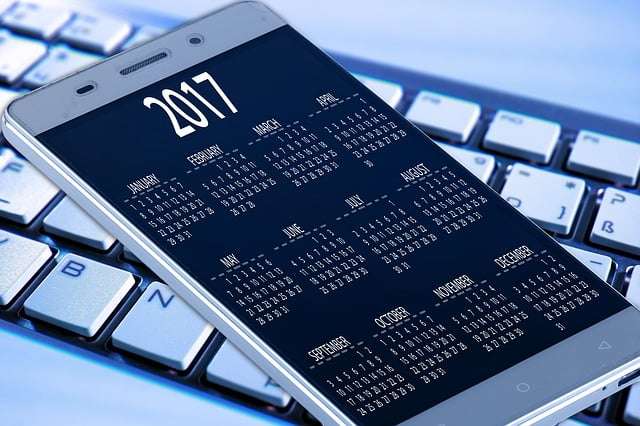 Slimme telefoon met kalenderweergave van 2017 op een toetsenbord, symboliseert planning en organisatie voor ISO-certificeringen in de defensiesector.