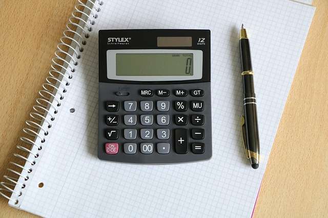 Calculator op een notitieblok met een pen, relevant voor het berekenen van offertes voor ISO-certificeringsaudits.