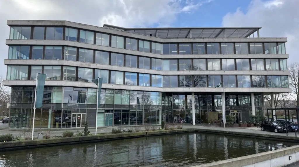 Modern kantoorgebouw met reflectie in water, illustrerend SCIOS-certificering en naleving van ISO 9001.