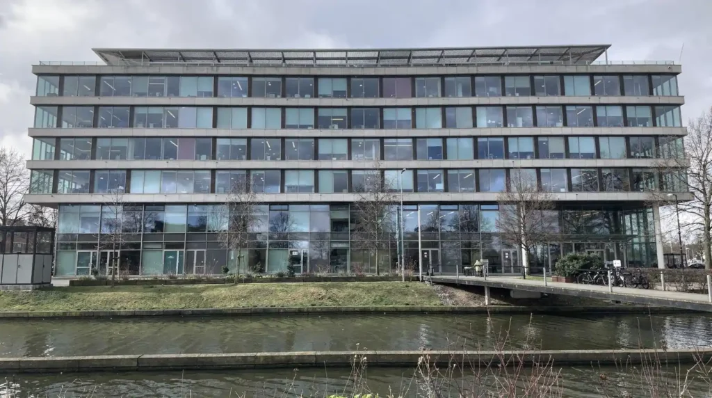 Modern kantoorgebouw met veel ramen en water, illustratie SCIOS certificering en scope bepaling.