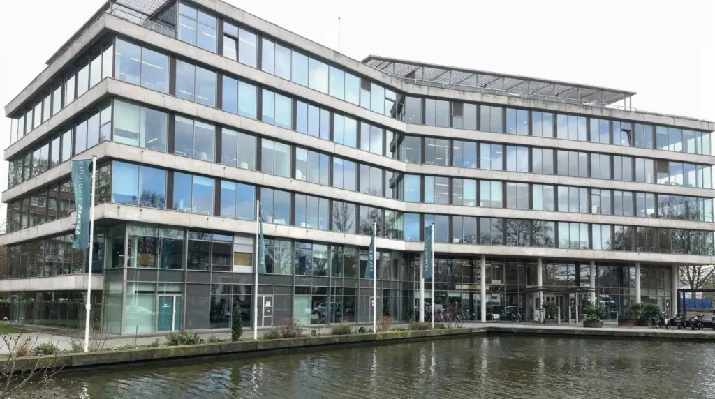 Modern kantoorgebouw met SCIOS-vlaggen en waterpartij, Stratlane NL gevestigd in Amsterdam.