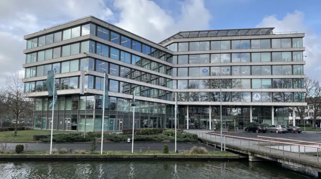Modern kantoorgebouw met Stratlane NL logo en vlaggen, illustrerend een betrouwbare certificeringsinstantie in Amsterdam.