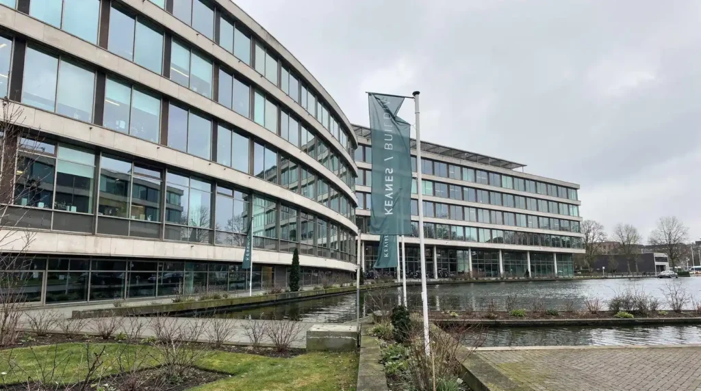 Modern kantoorgebouw met water en Stratlane NL vlag, Amsterdam.